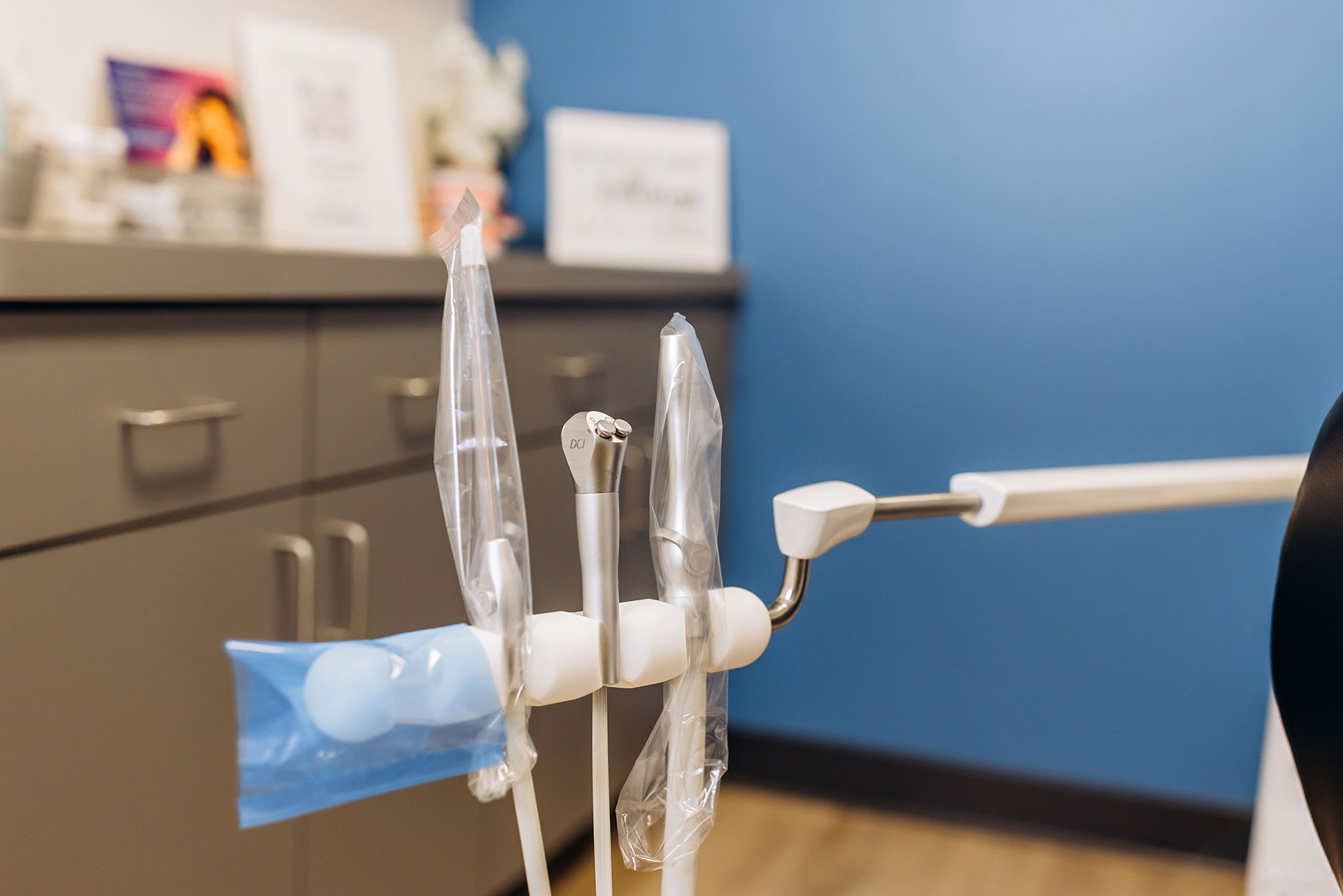 The image depicts a medical device with various parts attached to it, placed on a countertop in a room with blue walls, a desk, and a cabinet.