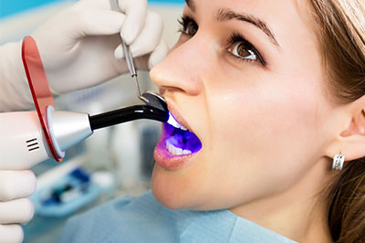 A woman receiving dental care with a purple device inserted into her mouth while seated in a dental chair.