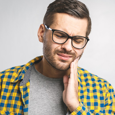 A man with glasses, a beard, and a yellow plaid shirt, looking upwards with his hand on his chin, possibly posing for the photo.