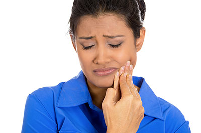 A woman with her eyes closed, showing signs of distress while holding her hand to her mouth.