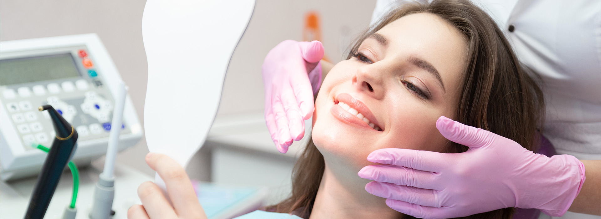 A woman receiving dental care with a dentist and hygienist, both wearing gloves and masks.