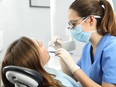 Dental hygienist performing dental work on patient s mouth, with focus on cleaning teeth.