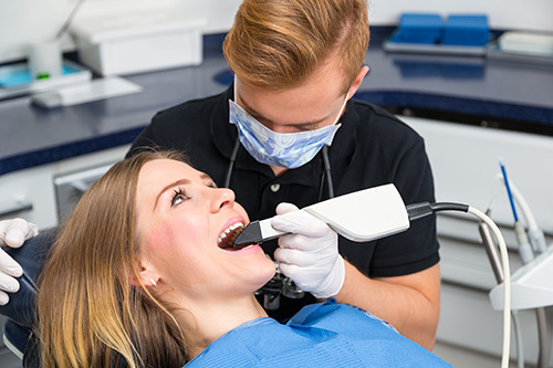 A dentist performing dental work on a patient in a dental office setting.