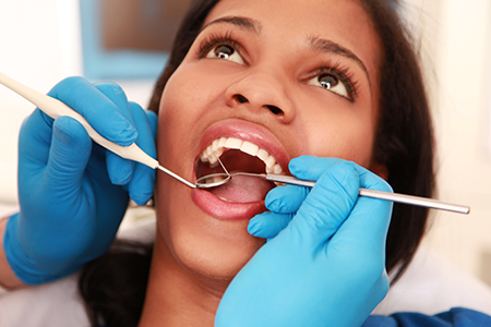 Woman receiving dental treatment with a dental hygienist performing procedure.