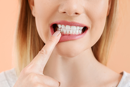 The image features a woman with her finger on her teeth, possibly indicating dental care or oral hygiene.